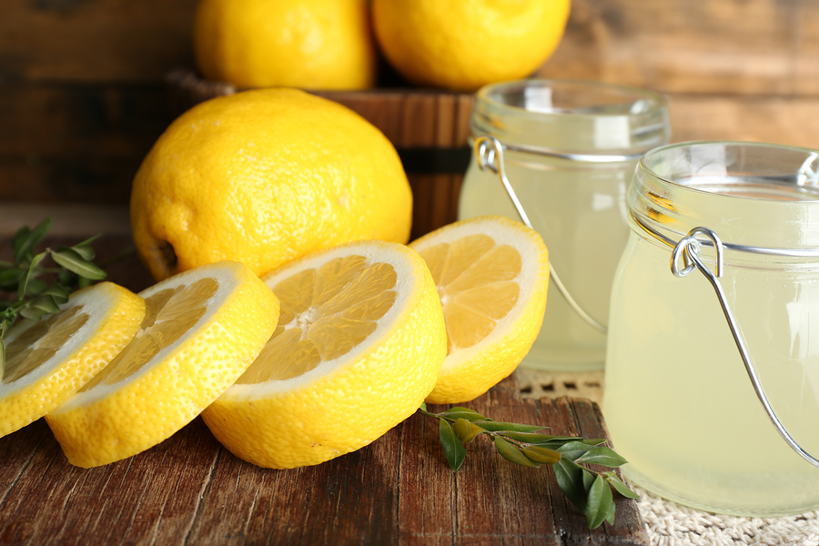 Still life with lemon juice and sliced lemons on wooden table, closeup