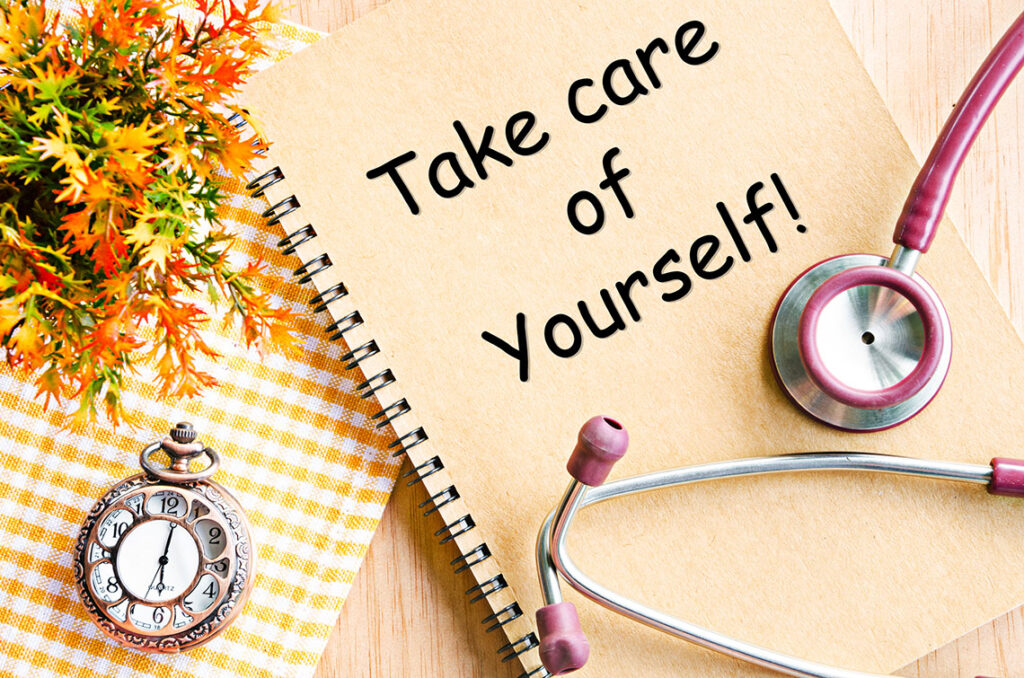 Take care of yourself on diary book and stethoscope with pocket watch on table.