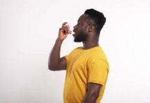 image of a black man wearing a yellow shirt and using an inhaler