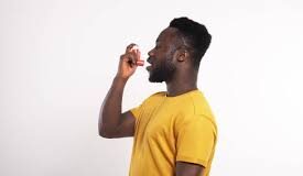 image of a black man wearing a yellow shirt and using an inhaler