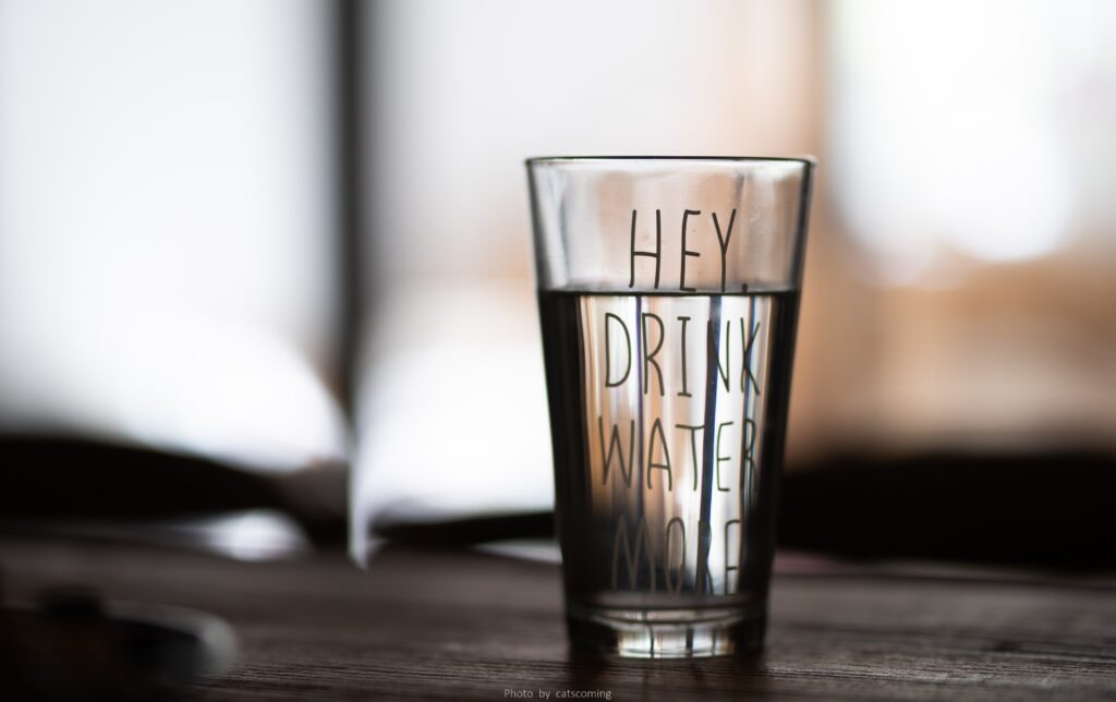 glass of water with the words " Hey drink water" On the glass