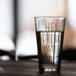 glass of water with the words " Hey drink water" On the glass