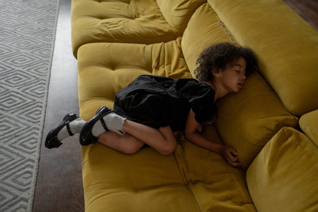 african child sleeping on a yellow sofa