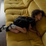 african child sleeping on a yellow sofa