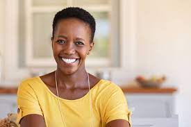 image of a dark skinned woman smiling while weariing a bright yellow shirt